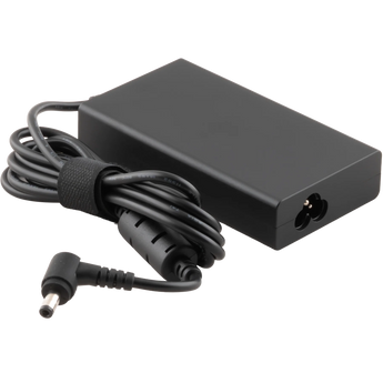 Schrägansicht des schwarzen XMG / SCHENKER 180 Watt Netzteils mit aufgewickeltem Kabel, integriertem Ferritkern und gewinkeltem Ausgangsstecker.
