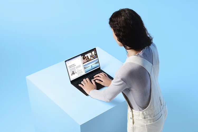 Eine Frau arbeitet an einem modernen Laptop auf einem hellblauen Podest