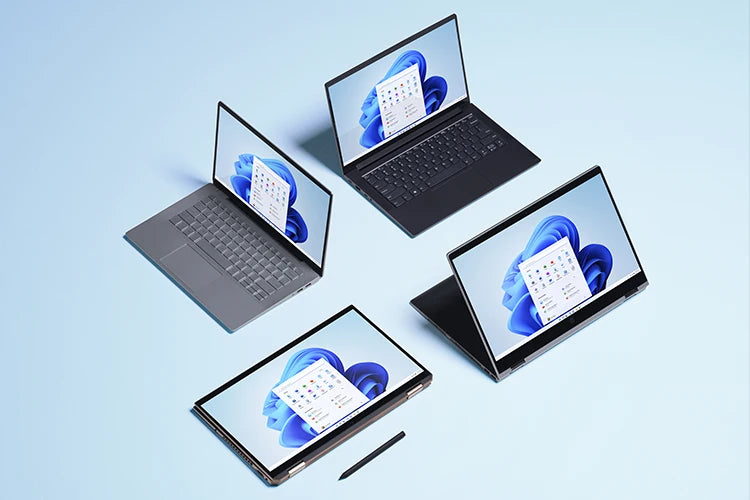 Vier verschiedene Laptops und Convertibles mit Windows 11 im modernen Design auf hellem, blauem Hintergrund angeordnet.