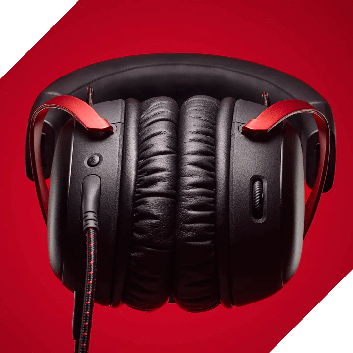 Schwarze Gaming-Headset-Ohrmuscheln mit roten Akzenten und Stoffkabel vor rotem Hintergrund