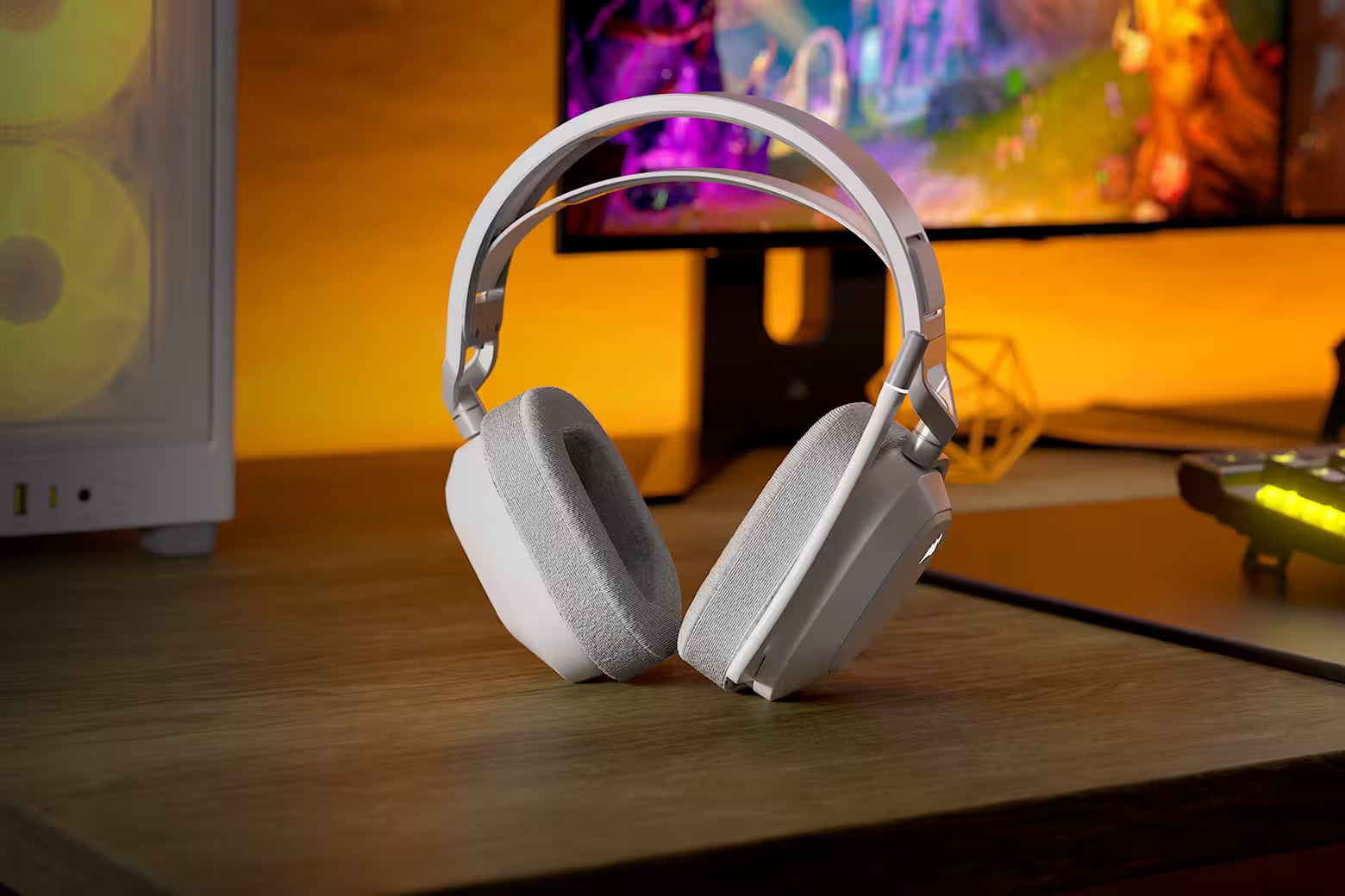 Weiße Gaming-Headset-Peripherie auf einem Gaming-Schreibtisch vor beleuchtetem Monitor