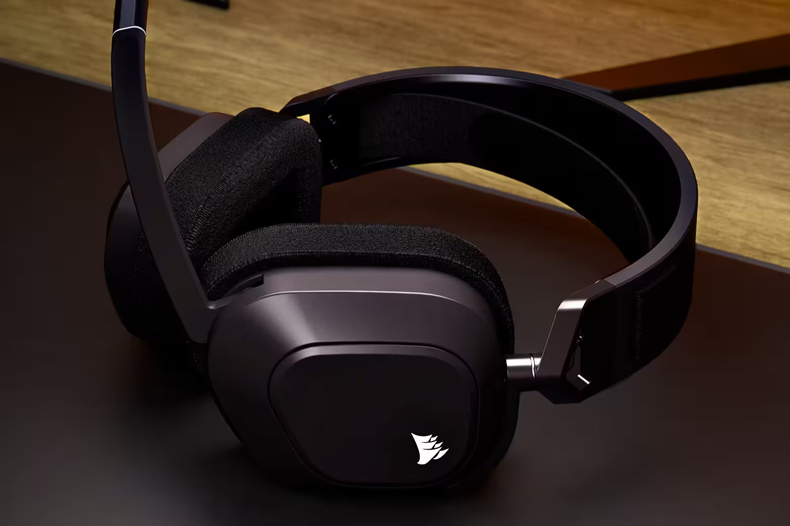 Schwarzes Gaming-Headset mit Mikrofonarm und beleuchtetem Logo auf einer dunklen Oberfläche