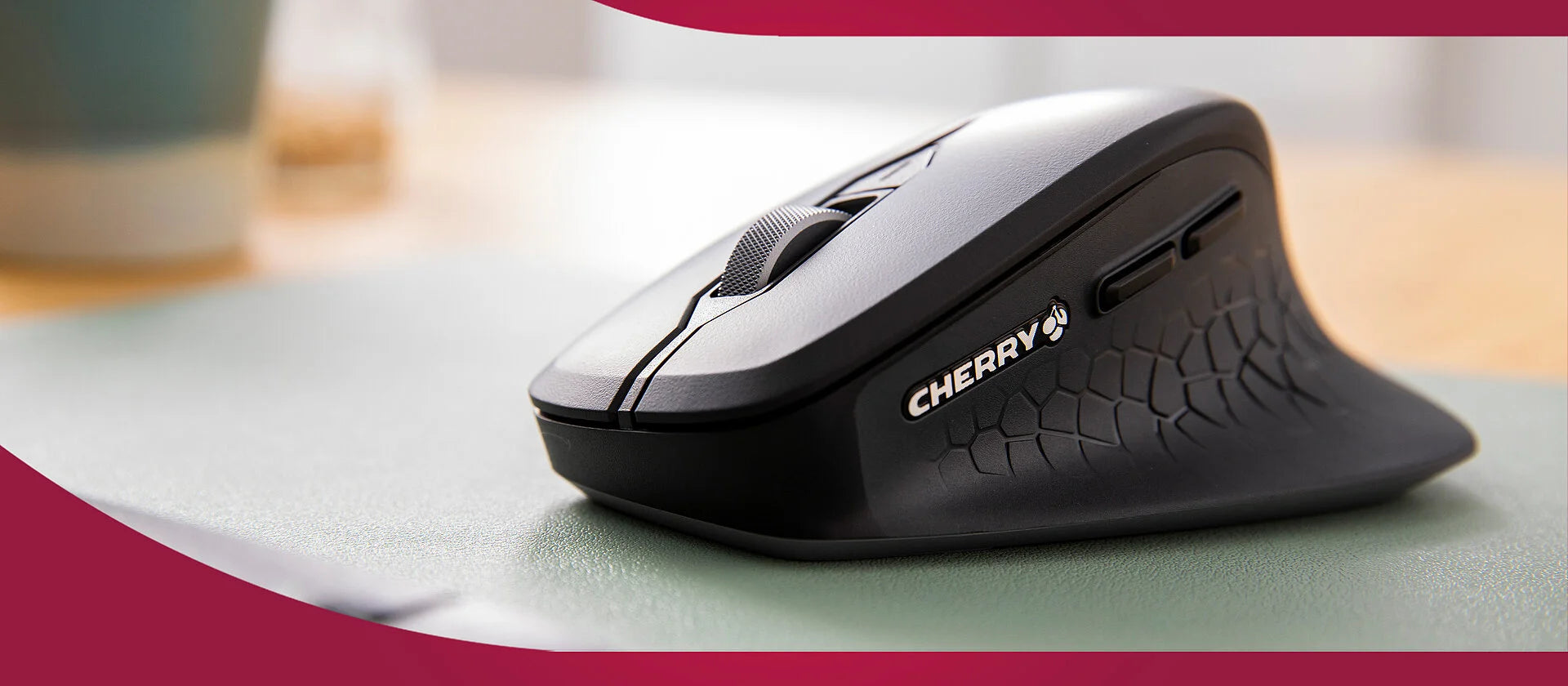 Ergonomische CHERRY Wireless-Maus in Schwarz mit Daumenablage und Metall-Mausrad auf einem Mauspad.
