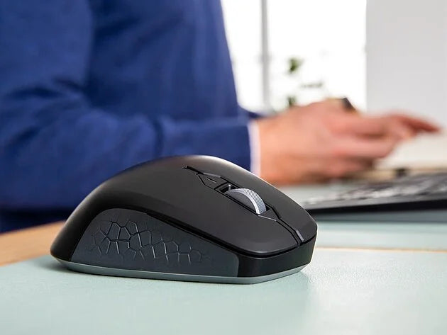 Schwarze ergonomische High-End-Computermaus auf einem Schreibtisch mit Person im Hintergrund