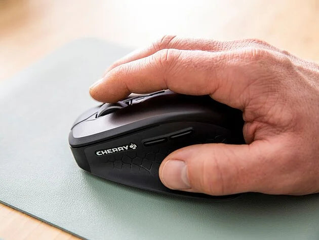 Hand bedient eine schwarze Cherry Computermaus auf einem Mauspad.