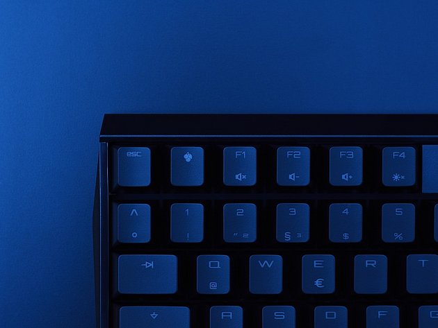 Nahaufnahme der beleuchteten Gaming-Tastatur eines Laptops vor blauem Hintergrund