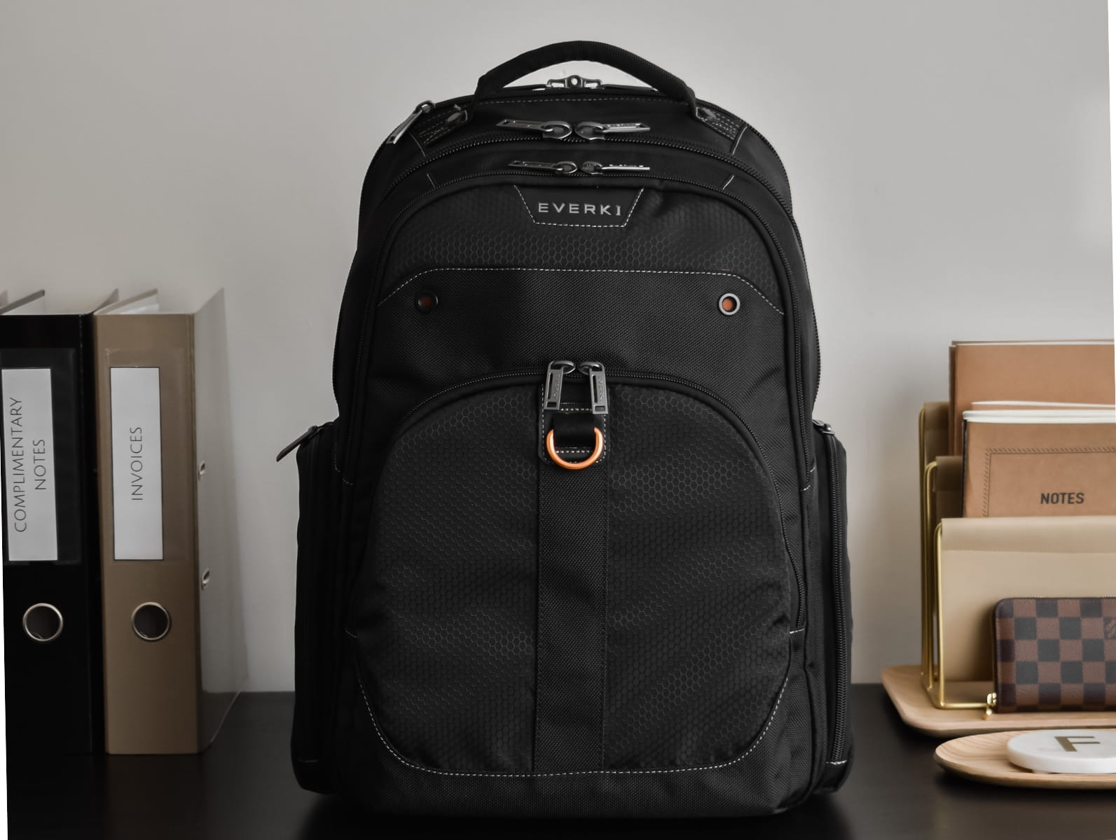 Schwarzer EVERKI Laptop-Rucksack auf einem Schreibtisch mit Ordnern und Notizbüchern im Hintergrund.