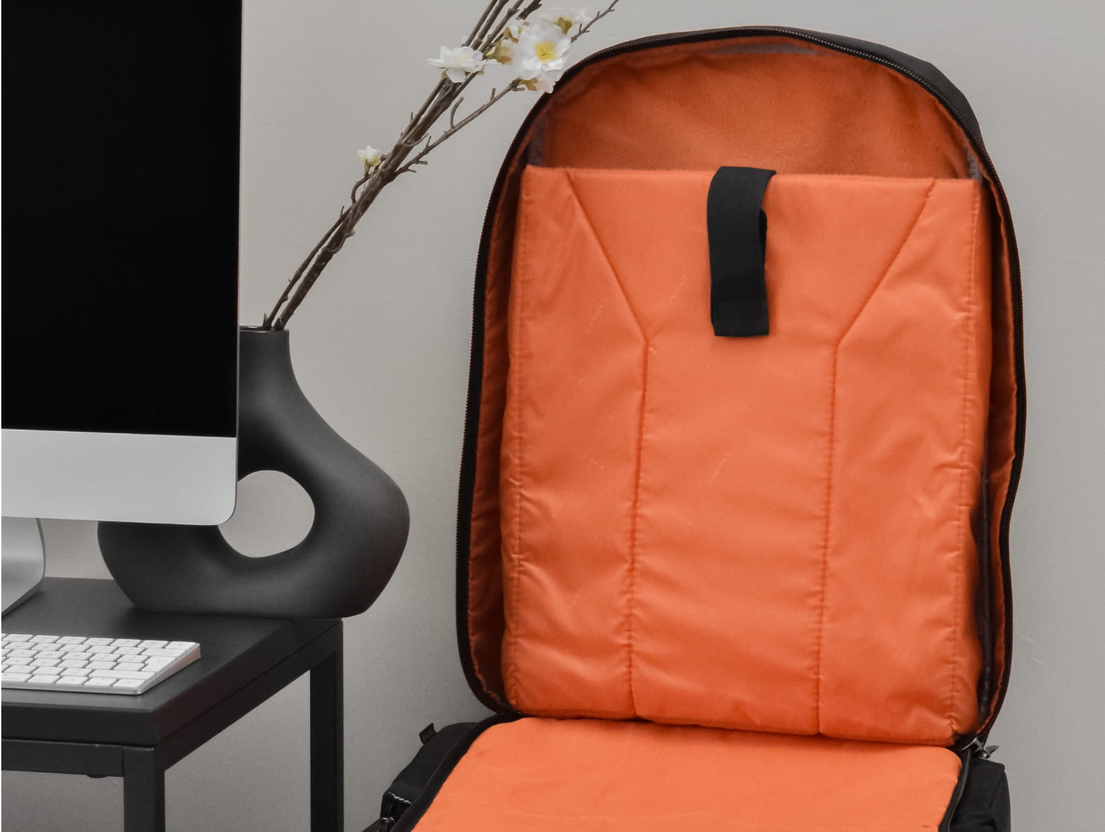 Geöffneter Laptop-Rucksack mit leuchtend orangen Innenfächern und gepolstertem Notebook-Fach auf einem Schreibtisch