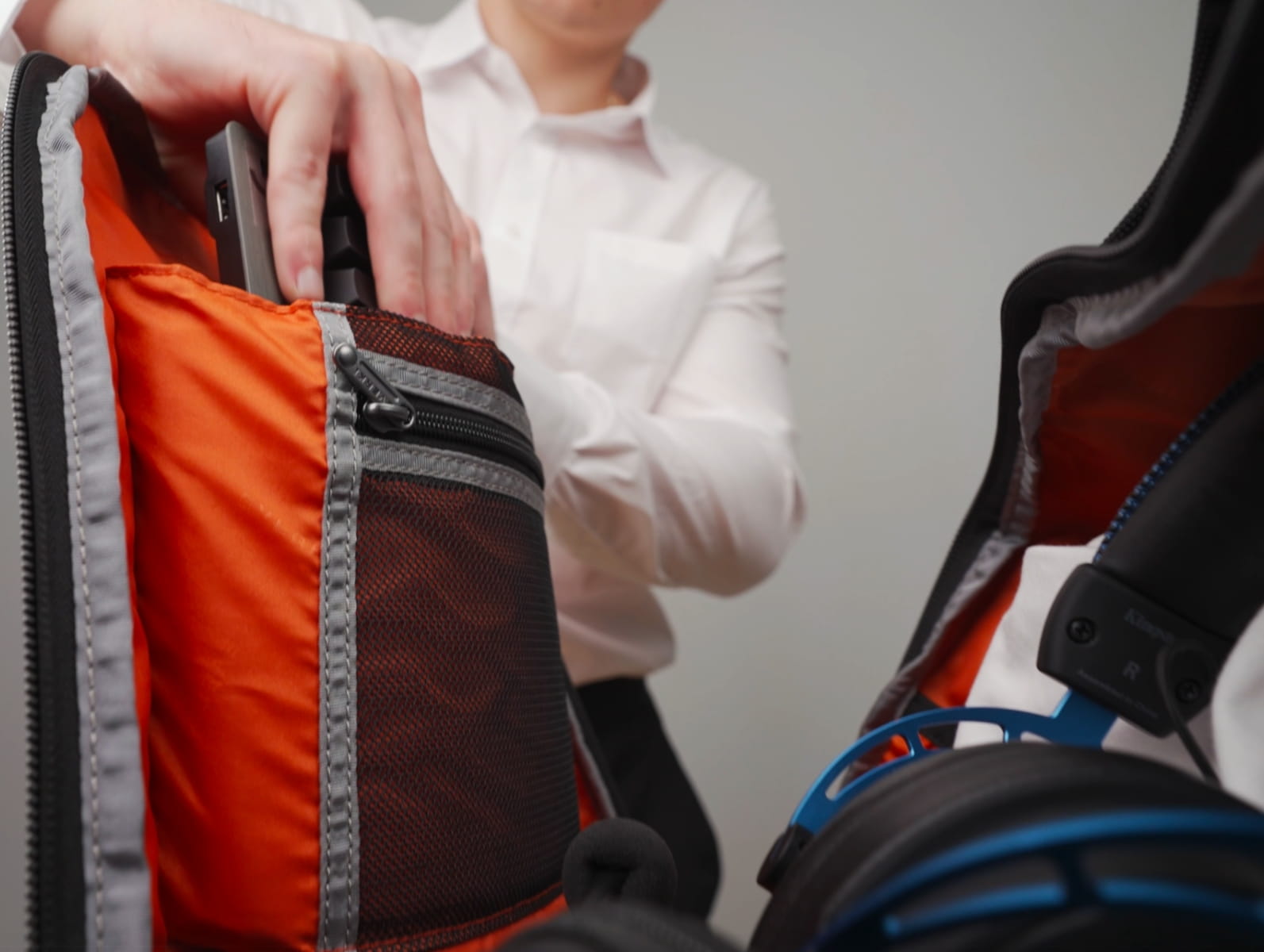 Geschäftsmann packt Gaming-Laptop und Peripherie in einen gut gefüllten Rucksack