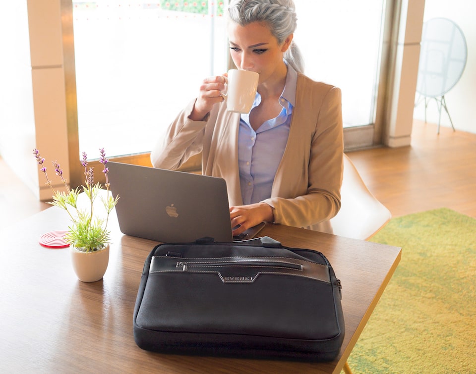 Frau arbeitet am Laptop im Café mit schwarzer Everki Laptoptasche auf dem Tisch.