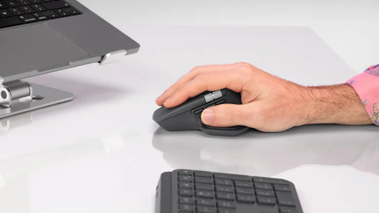 Hand bedient eine ergonomische High-End-Computermaus auf einem hellen Schreibtisch neben Laptop und Tastatur
