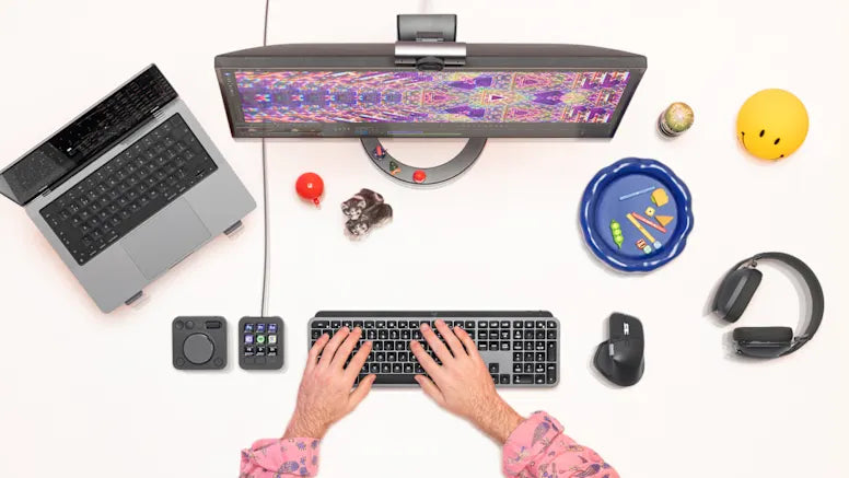 Vogelperspektive auf einen modernen Arbeitsplatz mit Laptop, Curved-Monitor, Tastatur, Maus und Kopfhörern.