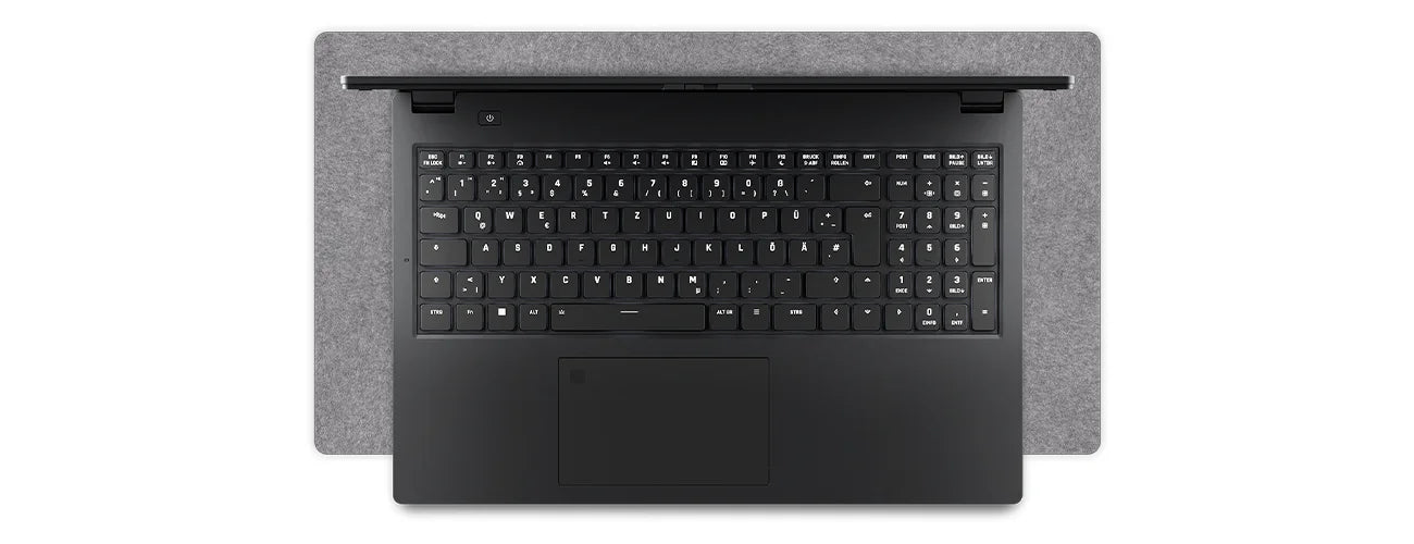 Draufsicht auf die schwarze Tastatur und das Touchpad eines High-End Laptops auf einer grauen Schreibtischunterlage