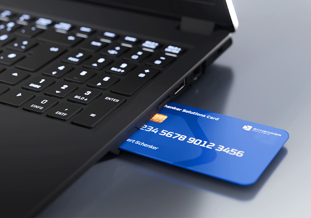 Eine blaue Smartcard steckt im integrierten Kartenleser eines schwarzen XMG Laptops mit beleuchteter Tastatur.