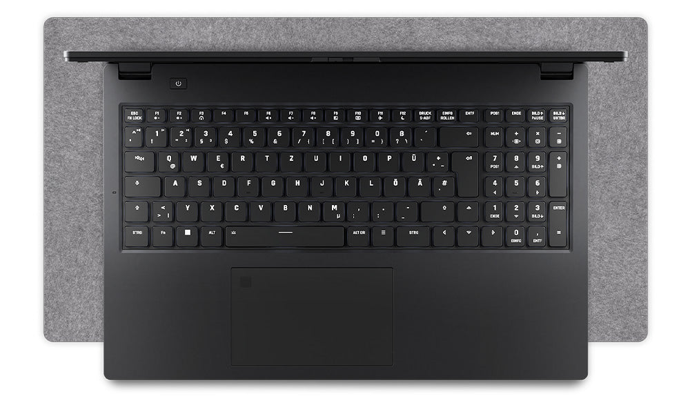 Draufsicht auf die deutsche Tastatur und das Touchpad eines schwarzen High-End Laptops auf einer grauen Filz-Schreibtischunterlage