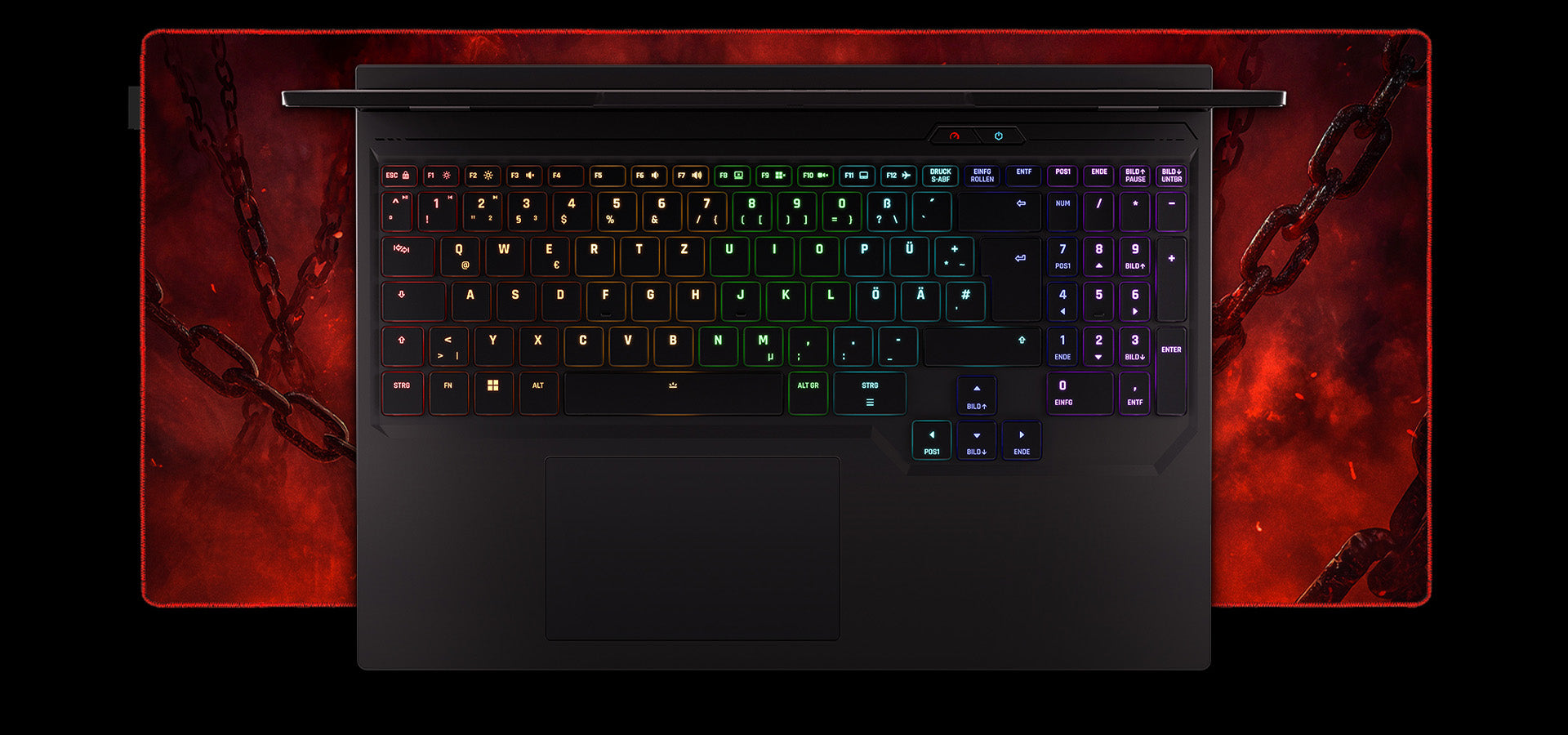 Draufsicht auf die RGB-beleuchtete Tastatur eines High-End Gaming-Laptops mit deutschem Layout vor rotem Ketten-Mauspad