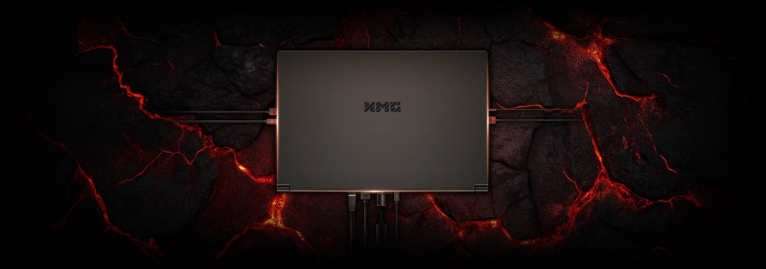 XMG Laptop von oben auf einem feurigen Lavagestein-Hintergrund mit angeschlossenen Kabeln