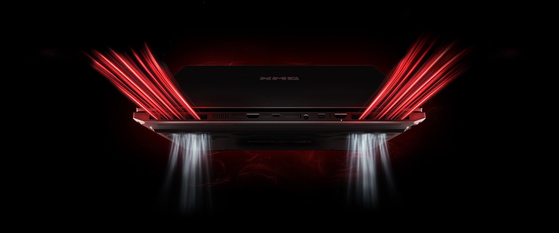 Rückseite eines XMG High-End-Gaming-Laptops mit sichtbaren Anschlüssen und rotem Lichtstrahleffekt der Kühlung
