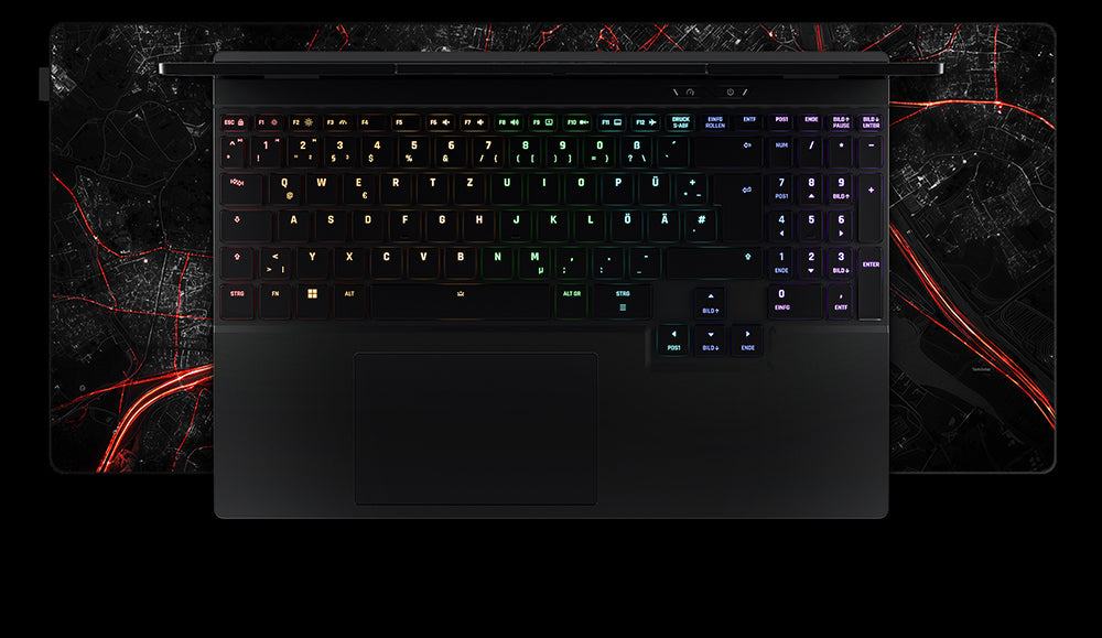 Draufsicht auf die RGB-Tastatur und das Touchpad eines XMG Laptops auf einem großen Gaming-Mauspad mit rotem Stadtkarten-Design.