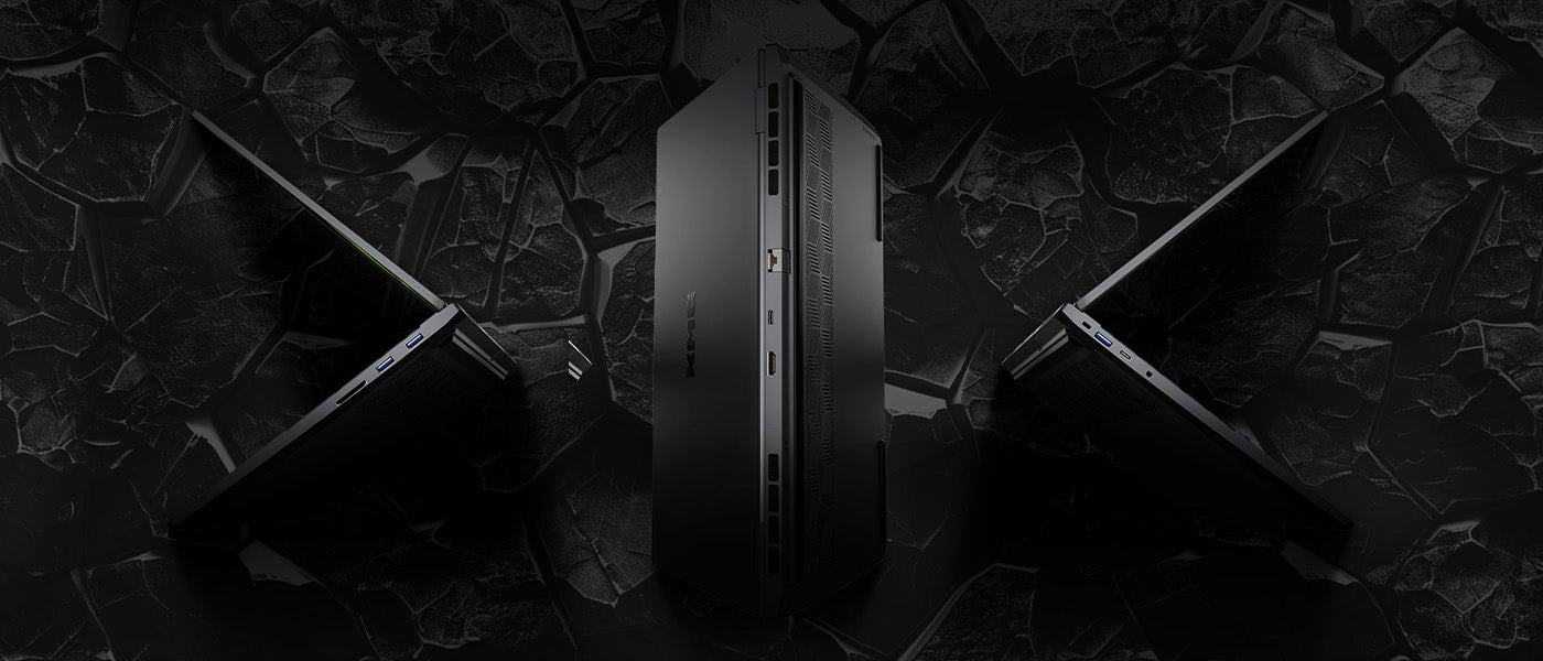 Drei High-End Gaming-Laptops in schwarzem Design vor einem dunklen, felsigen Hintergrund.