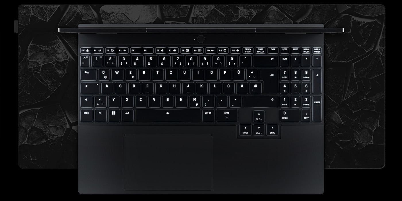 Draufsicht auf die beleuchtete Tastatur eines High-End Gaming-Laptops auf einer dunklen Schreibtischunterlage