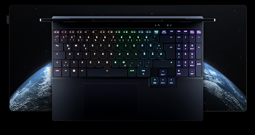 Draufsicht auf die beleuchtete RGB-Tastatur eines High-End Gaming-Laptops auf einem XXL-Mauspad mit Weltraummotiv.