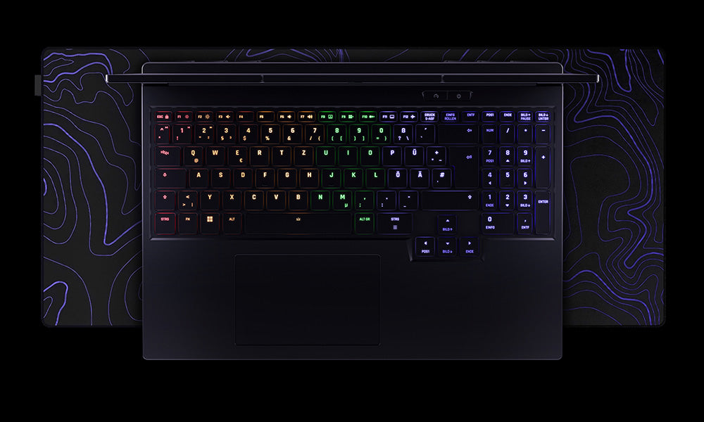 Draufsicht auf die beleuchtete RGB-Tastatur eines High-End Gaming-Laptops auf einer großen Gaming-Mausmatte.