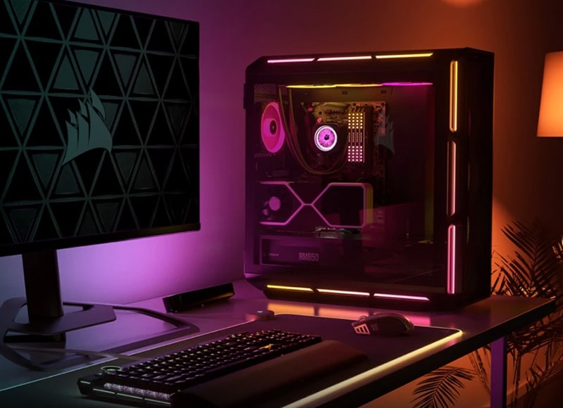 High-End Gaming-PC mit RGB-Beleuchtung auf einem Schreibtisch neben Monitor, Tastatur und Maus.