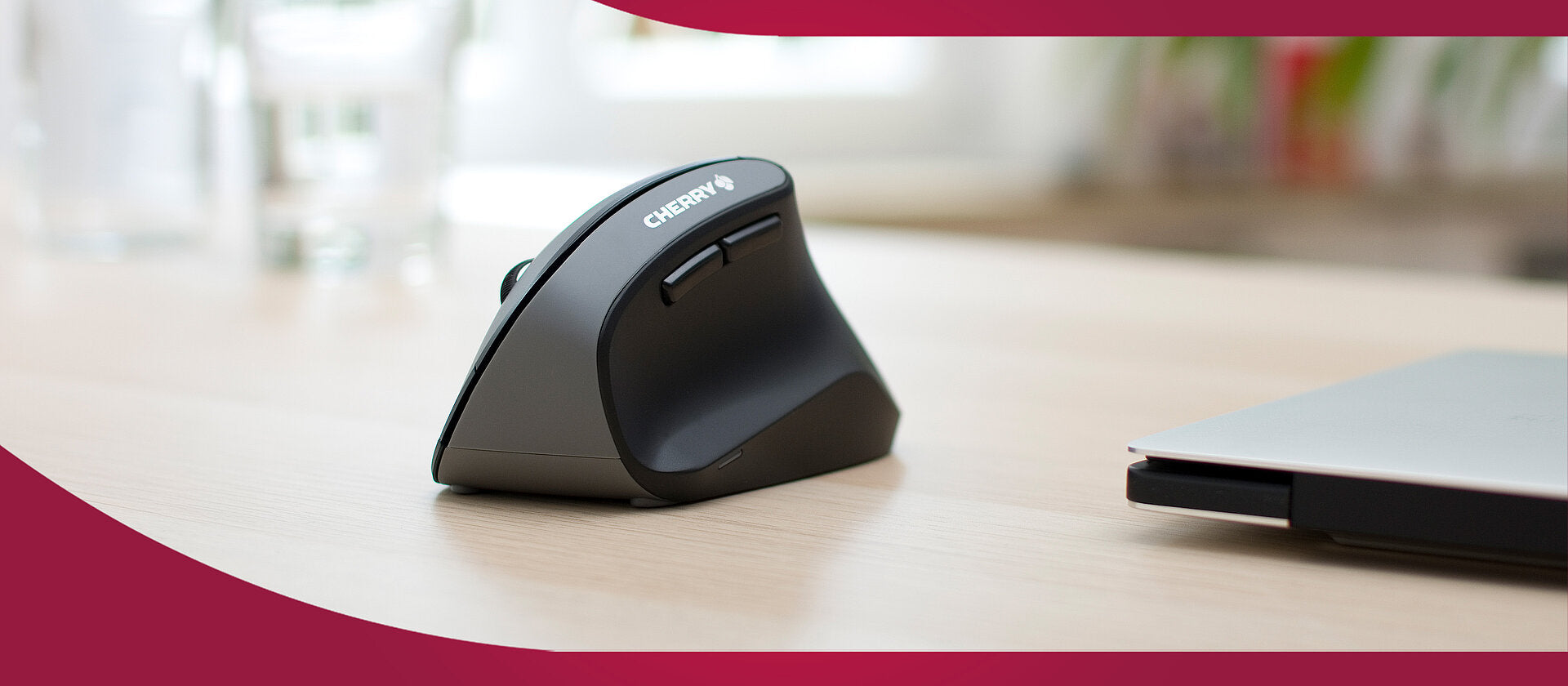 Ergonomische CHERRY Vertikal-Maus in Grau-Schwarz auf einem Holztisch im Büro.