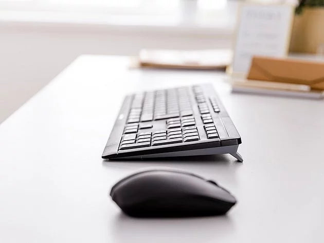 Schwarze Computermaus und Tastatur auf hellem Schreibtisch