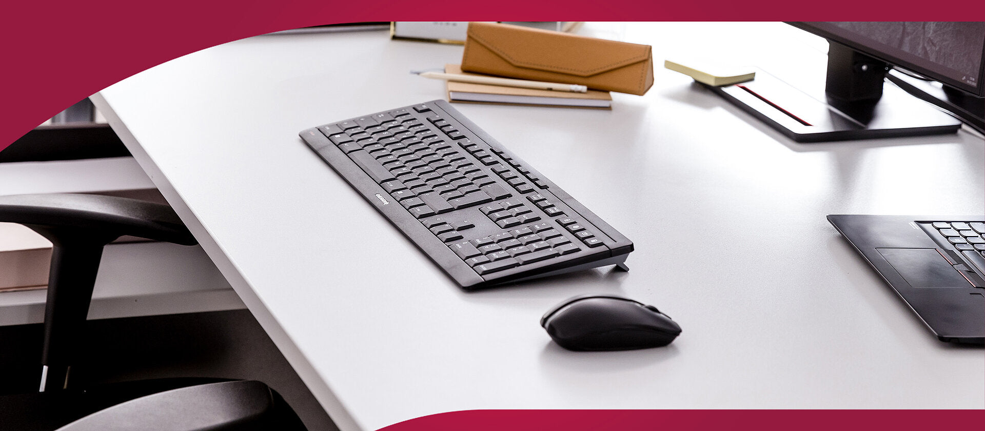 Schwarze Computermaus und Tastatur auf einem modernen, hellen Schreibtisch im Büro.