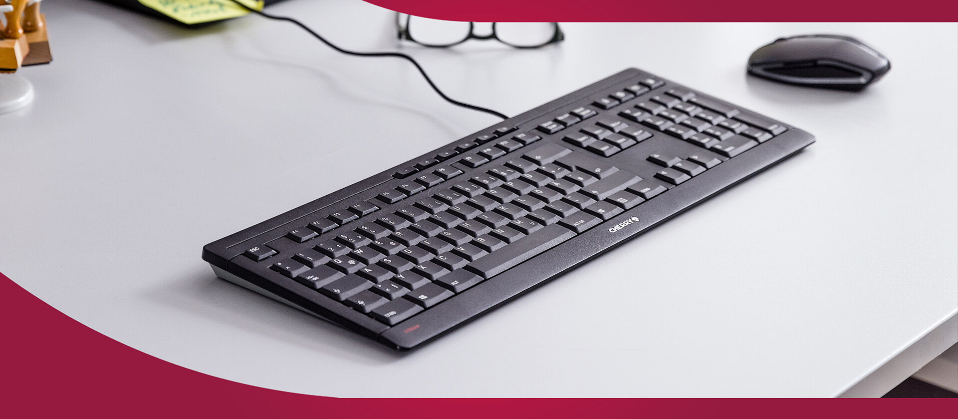 Schwarze Cherry PC-Tastatur und Computermaus auf einem hellen Schreibtisch in einem modernen Büro.