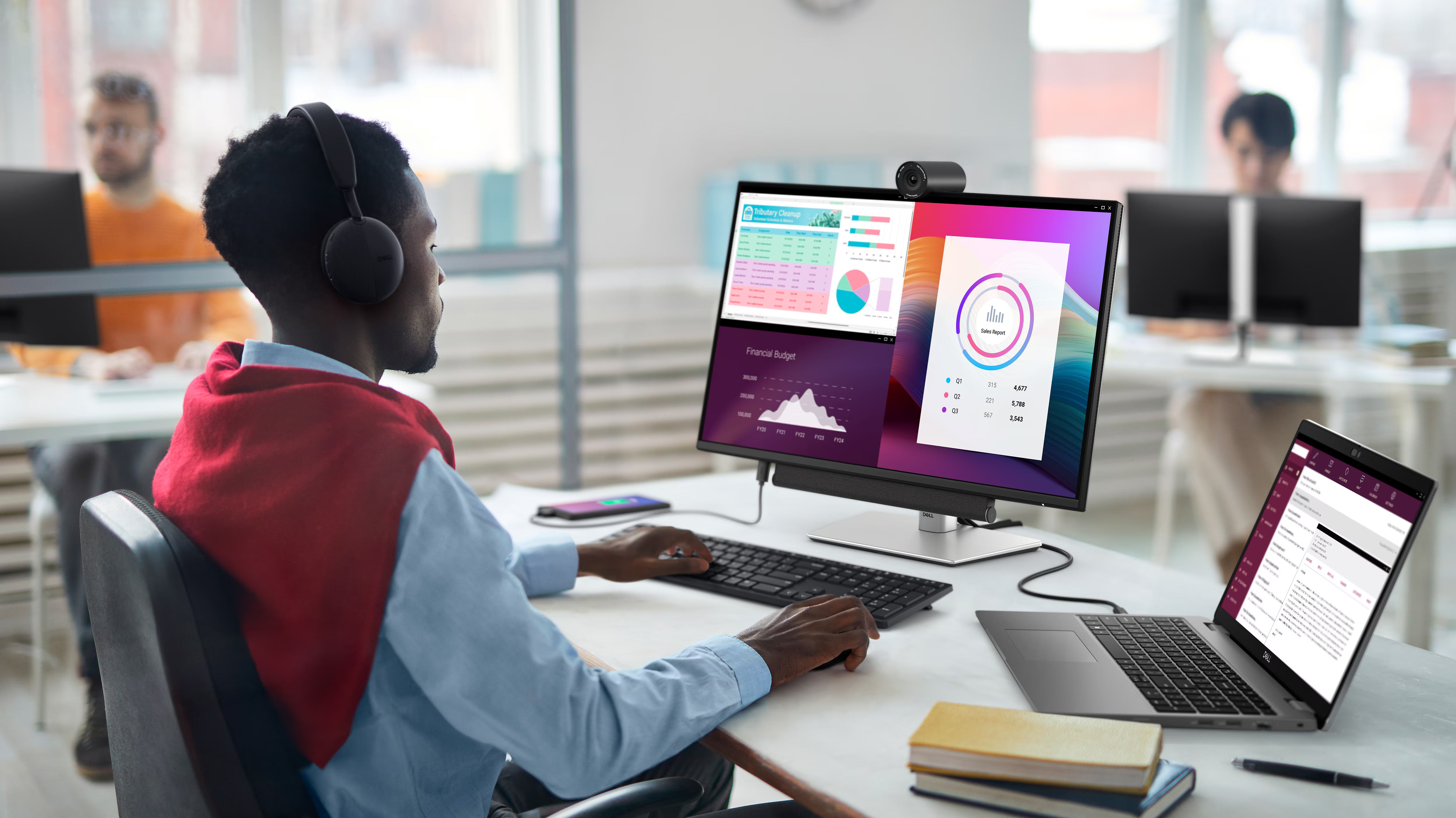 Mitarbeiter arbeitet im modernen Büro an einem Dell Monitor mit Webcam und verbundenem Laptop