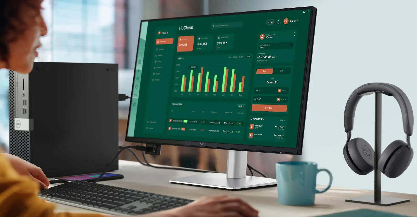 Person arbeitet an einem modernen Dell Monitor mit grünem Dashboard-Display und Gaming-Peripherie auf dem Schreibtisch.