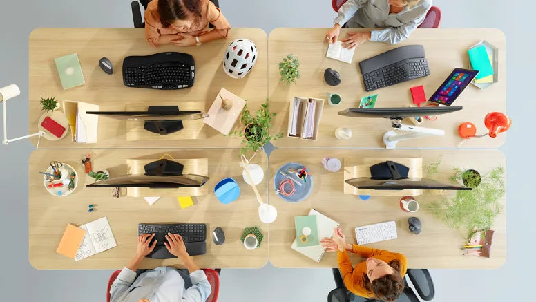 Vogelperspektive auf moderne Büroarbeitsplätze mit Monitoren, ergonomischer Peripherie und Hardware.