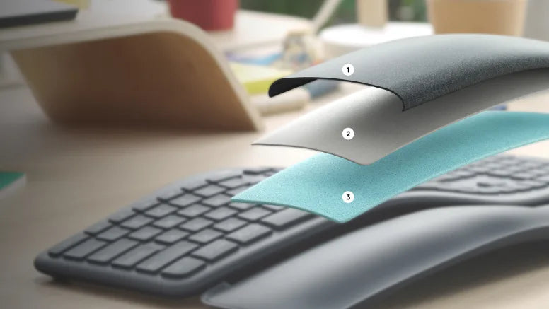 Explosionszeichnung der mehrschichtigen Handballenauflage einer ergonomischen Tastatur auf einem Holzschreibtisch