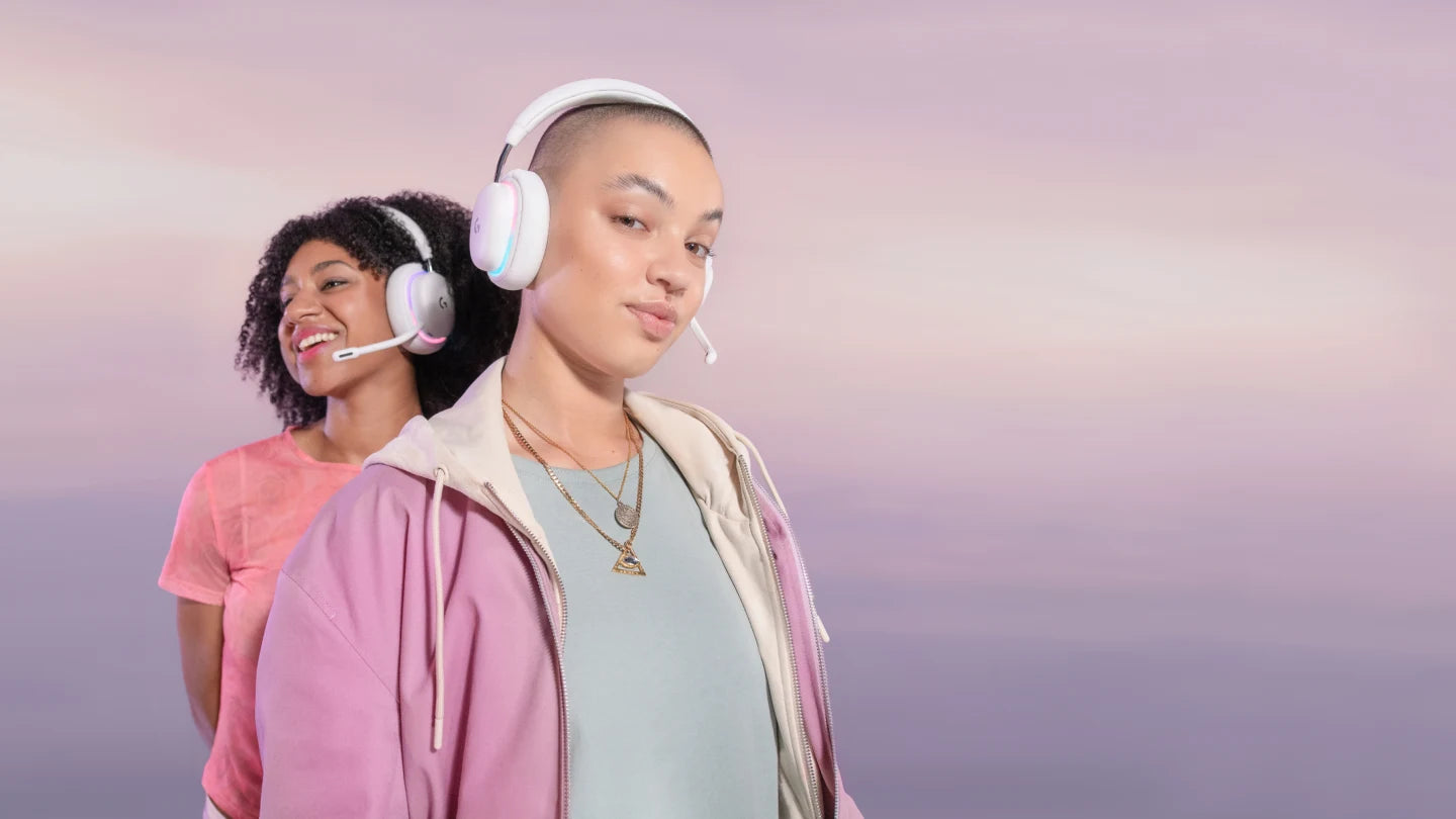Zwei junge Frauen tragen weiße Gaming-Headsets vor rosa-violettem Hintergrund.