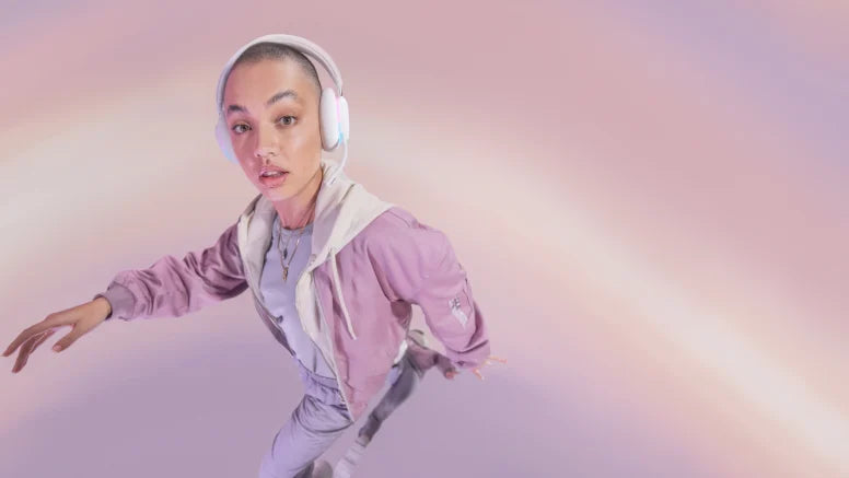 Junge Person mit Gaming-Headset und rosa Jacke posiert dynamisch vor rosa Hintergrund.