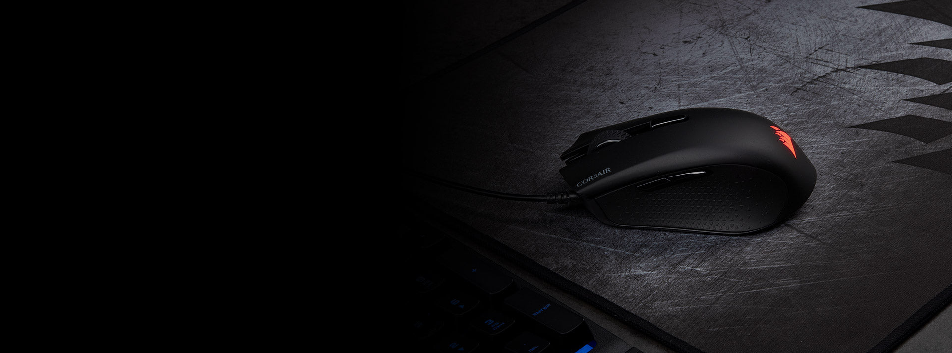 Schwarze Corsair Gaming-Maus mit roter LED-Beleuchtung auf einem Mousepad im Dunkeln