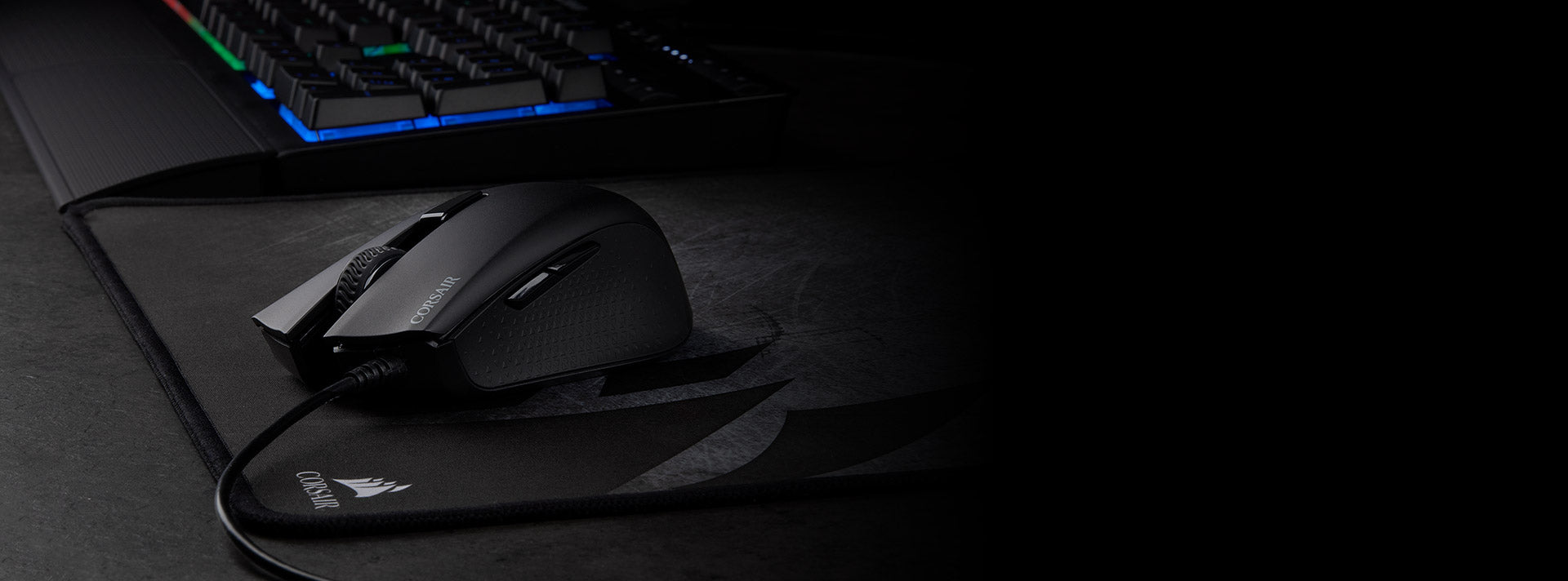 Corsair Gaming-Maus und Tastatur auf einem Mauspad auf dunklem Schreibtisch