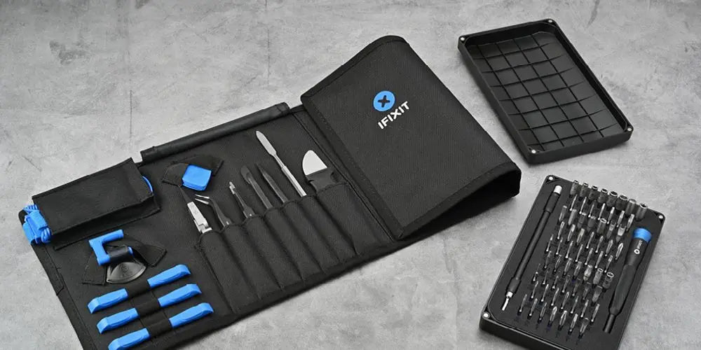 Ausgebreitetes iFixit Werkzeugset für Hardware-Reparaturen mit geöffneter Tasche, Bit-Box und Sortierschale auf grauem Untergrund.
