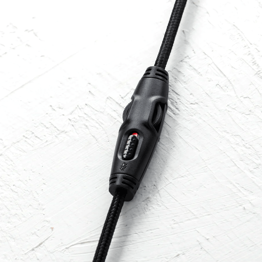 Nahaufnahme der Inline-Fernbedienung eines Gaming-Headset-Kabels mit Lautstärkeregler und Mute-Schalter auf weißem Hintergrund.