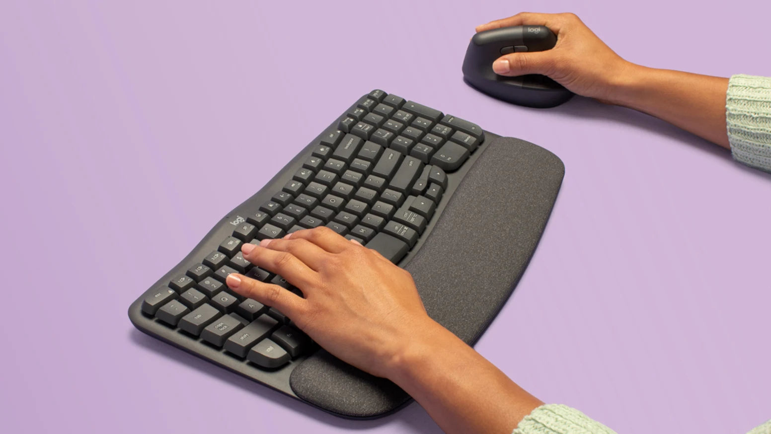 Hände bedienen eine ergonomische Logitech-Tastatur mit Handballenauflage und eine vertikale Maus auf lila Hintergrund.