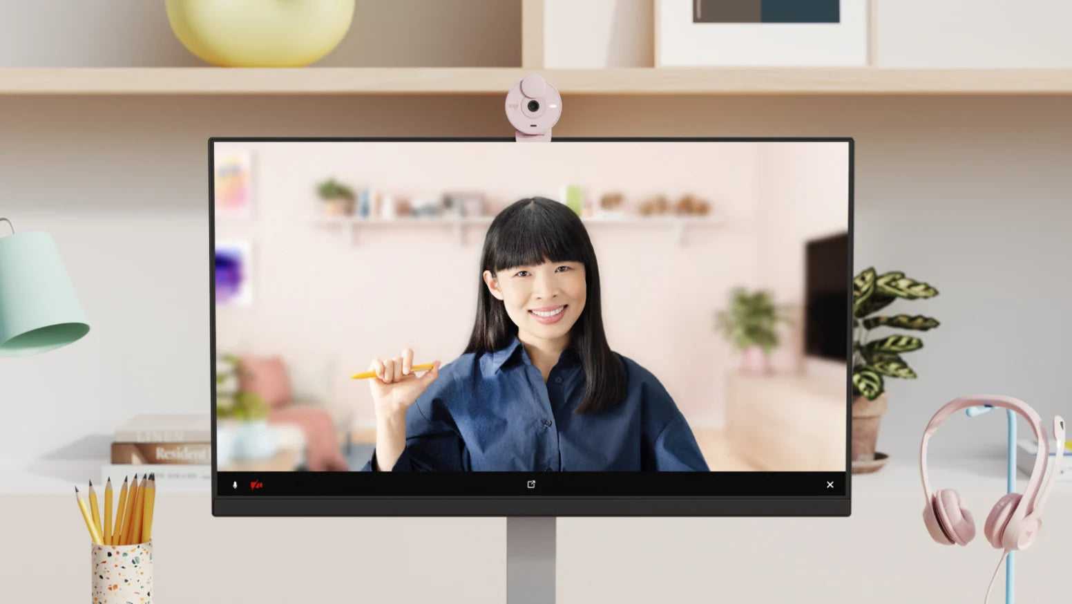 Rosa Webcam montiert auf einem modernen Monitor zeigt eine Frau bei einer Videokonferenz