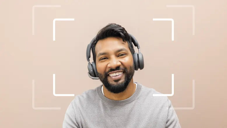 Lächelnder Mann mit Bart und Over-Ear-Headset vor neutralem Hintergrund mit Fokusrahmen.