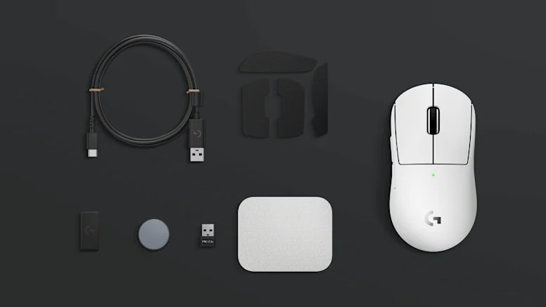 Weiße Logitech Gaming-Maus mit Ladekabel, USB-Empfänger und weiterem Zubehör auf dunklem Untergrund.
