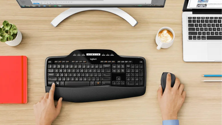Ergonomische Logitech-Tastatur mit Handballenauflage und Maus auf einem holzfarbenen Schreibtisch.