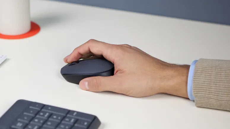 Hand bedient eine ergonomische schwarze Computermaus auf einem hellen Schreibtisch neben einer Tastatur