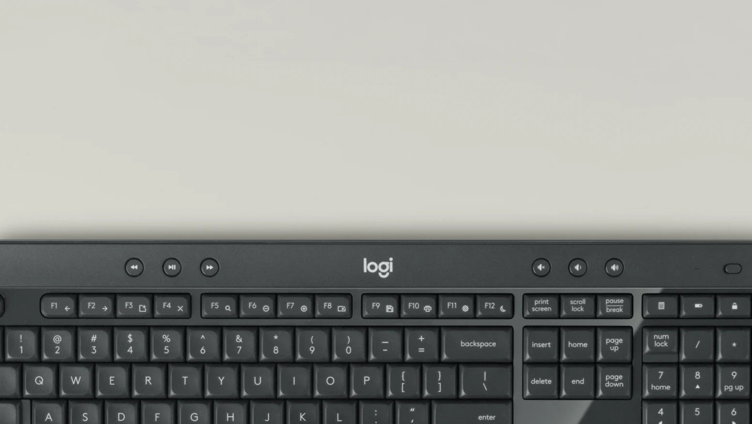 Nahaufnahme der schwarzen Logi Tastatur mit Medien- und Ziffernblock auf einem hellen Schreibtisch.