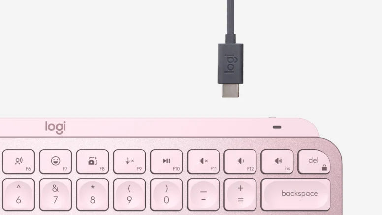 Nahaufnahme einer rosafarbenen Logitech-Tastatur mit darüber positioniertem USB-C-Ladekabel